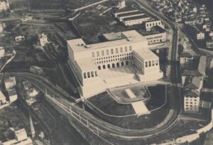 Veduta aerea dell'Edificio A con alle spalle il nuovo Edificio B e i padiglioni della Facoltà di Ingegneria costruiti durante la guerra, prima metà degli anni Cinquanta. Autore sconosciuto. Archivio dell'Università degli Studi di Trieste.